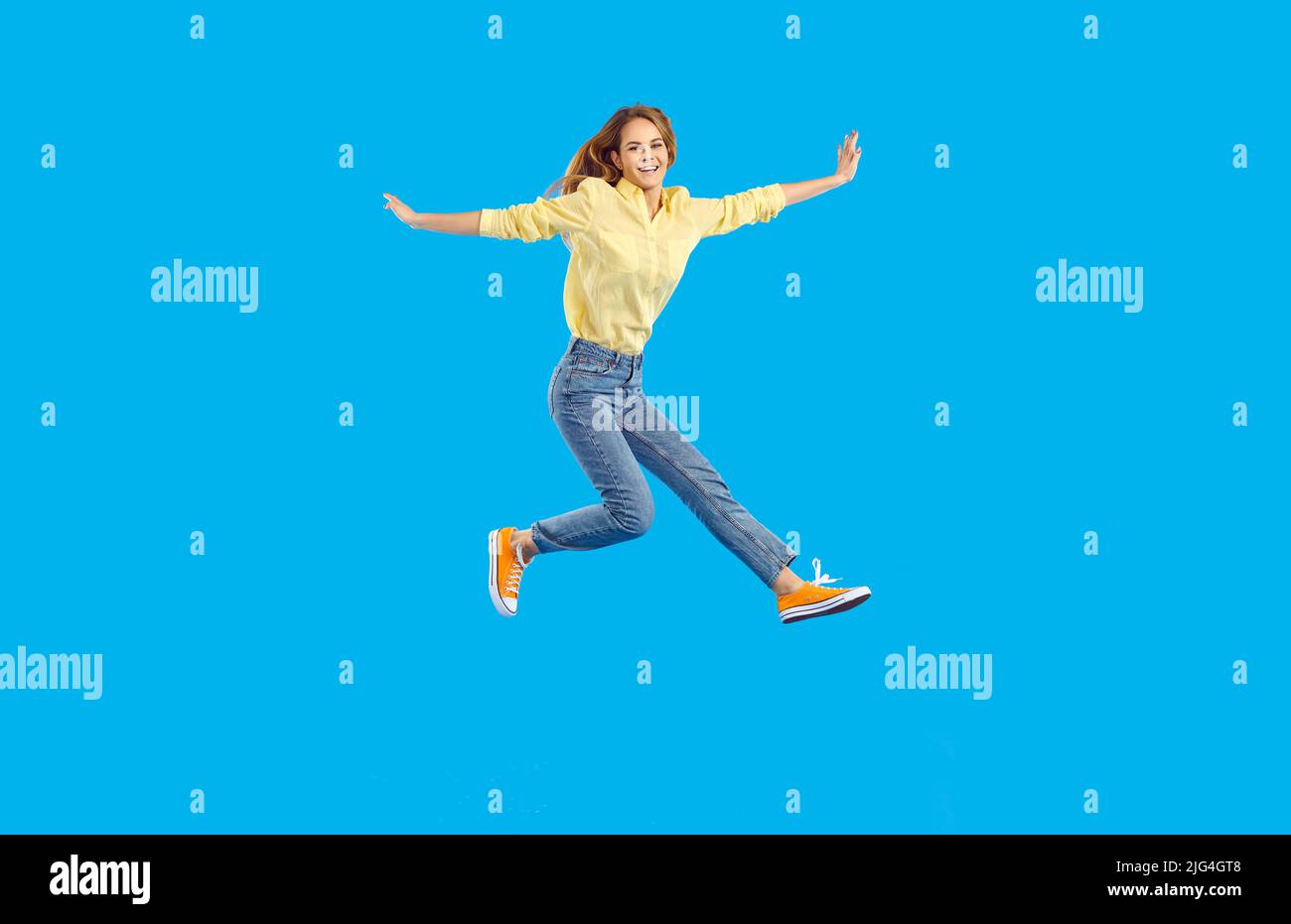 Full length body size view of nice attractive lovely glad cheerful wavy-haired woman jumping having fun rising hands up isolated on blue color Stock Photo