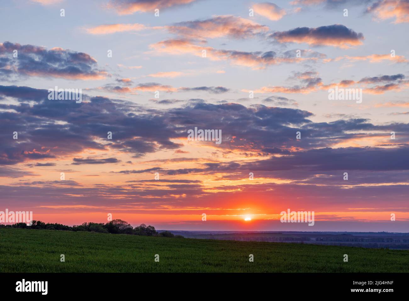 Landscape view to the sun and clouds over farming green fields Stock Photo