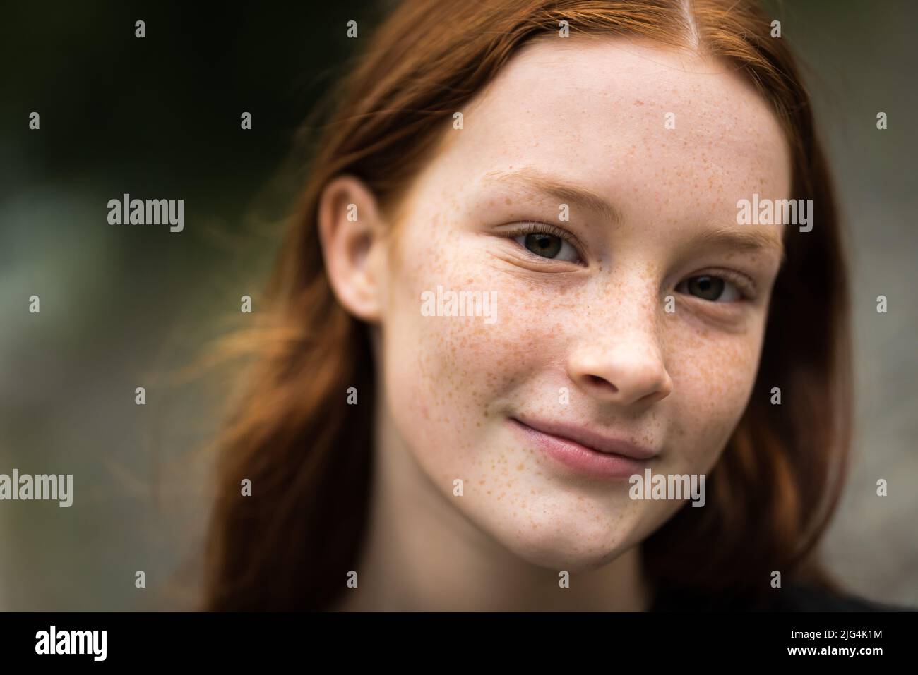 Red haired twelve year old girl with freckles posing with a city bokeh background, Jette, Belgium Stock Photo
