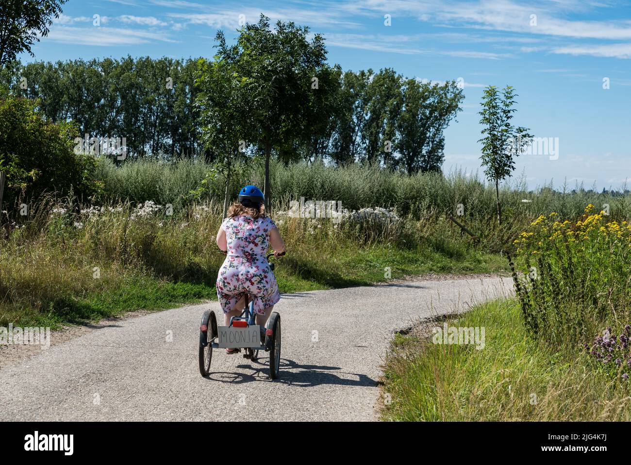 Young woman with Down syndrome driving on a tricycle through the fields at the Belgian countryside, Belgium Stock Photo