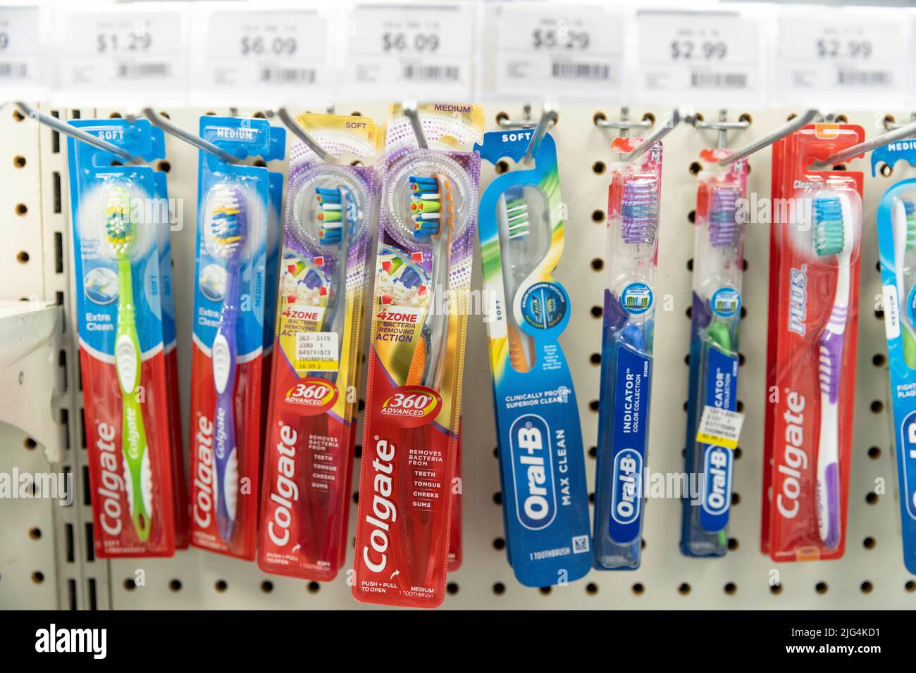 A row of Colgate and Oral B toothbrush packages hang on a display at a drug store Stock Photo