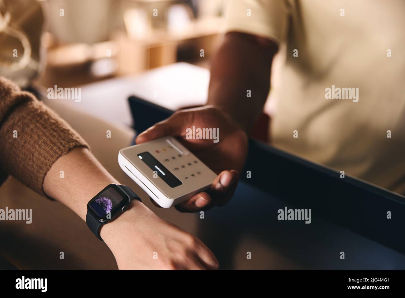 Customer Paying Using Smart Watch Mobile Payment NFC Contactless Technology In Retail Store Stock Photo