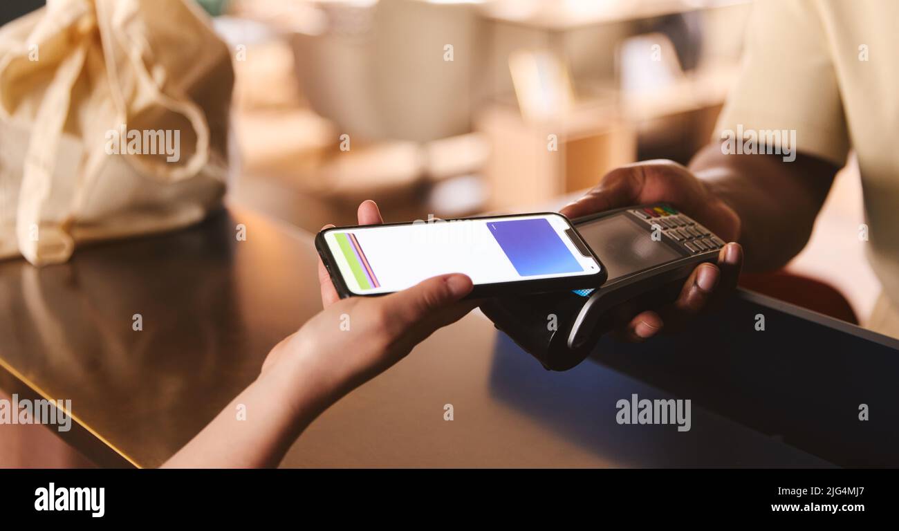 Customer Paying Using Smartphone Mobile Payment NFC Contactless Technology In Retial Store Stock Photo