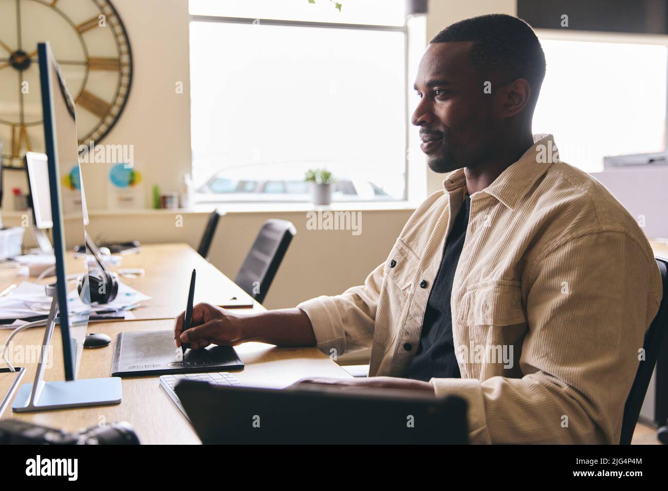 Young Black Male Advertising Marketing Or Design Creative In Modern Office Sitting At Desk Working On Computer Stock Photo
