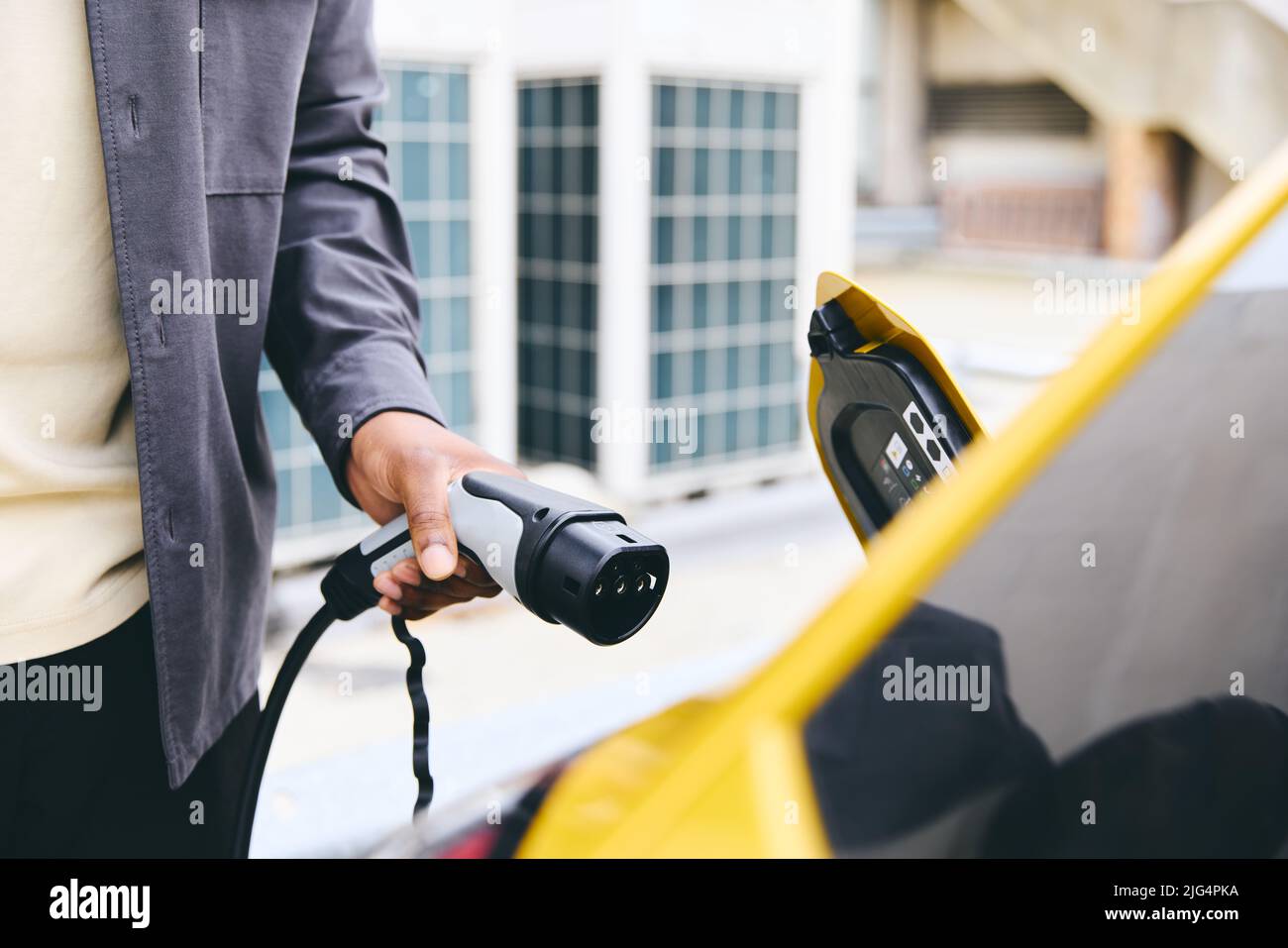 Hand Plugging In Electric Car Outside Office In Car Park Charging Stock Photo