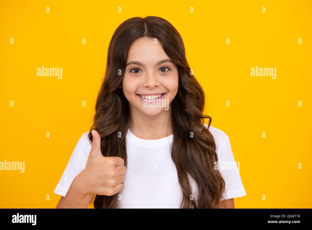 Optimistic cool teenager child girl with thumb up isolated on yellow background. Stock Photo