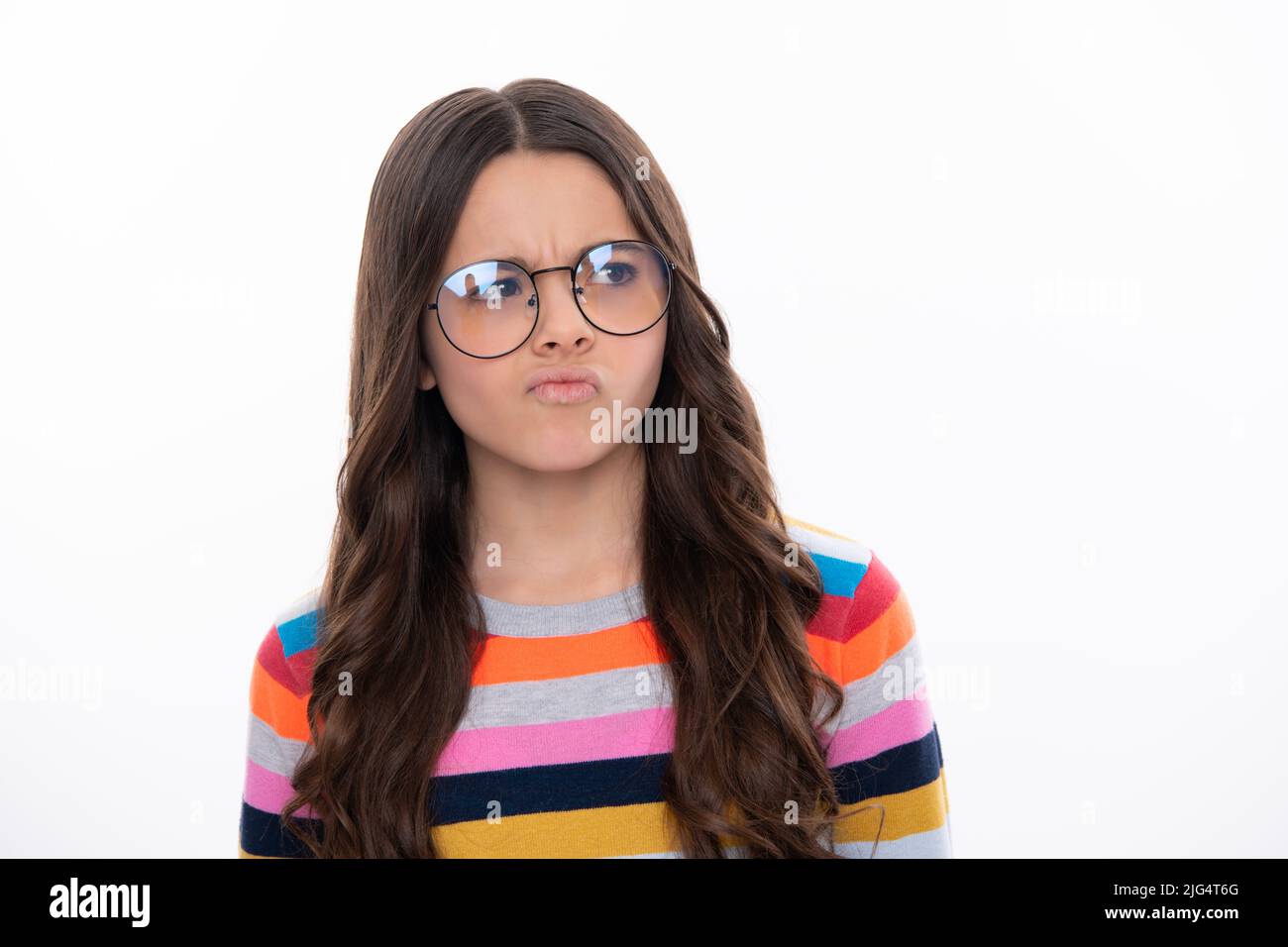 Childhood emotion anger and hate. Teenager girl frowning upset because of problem. Mad young girl isolated in studio background. Furious child. Stock Photo