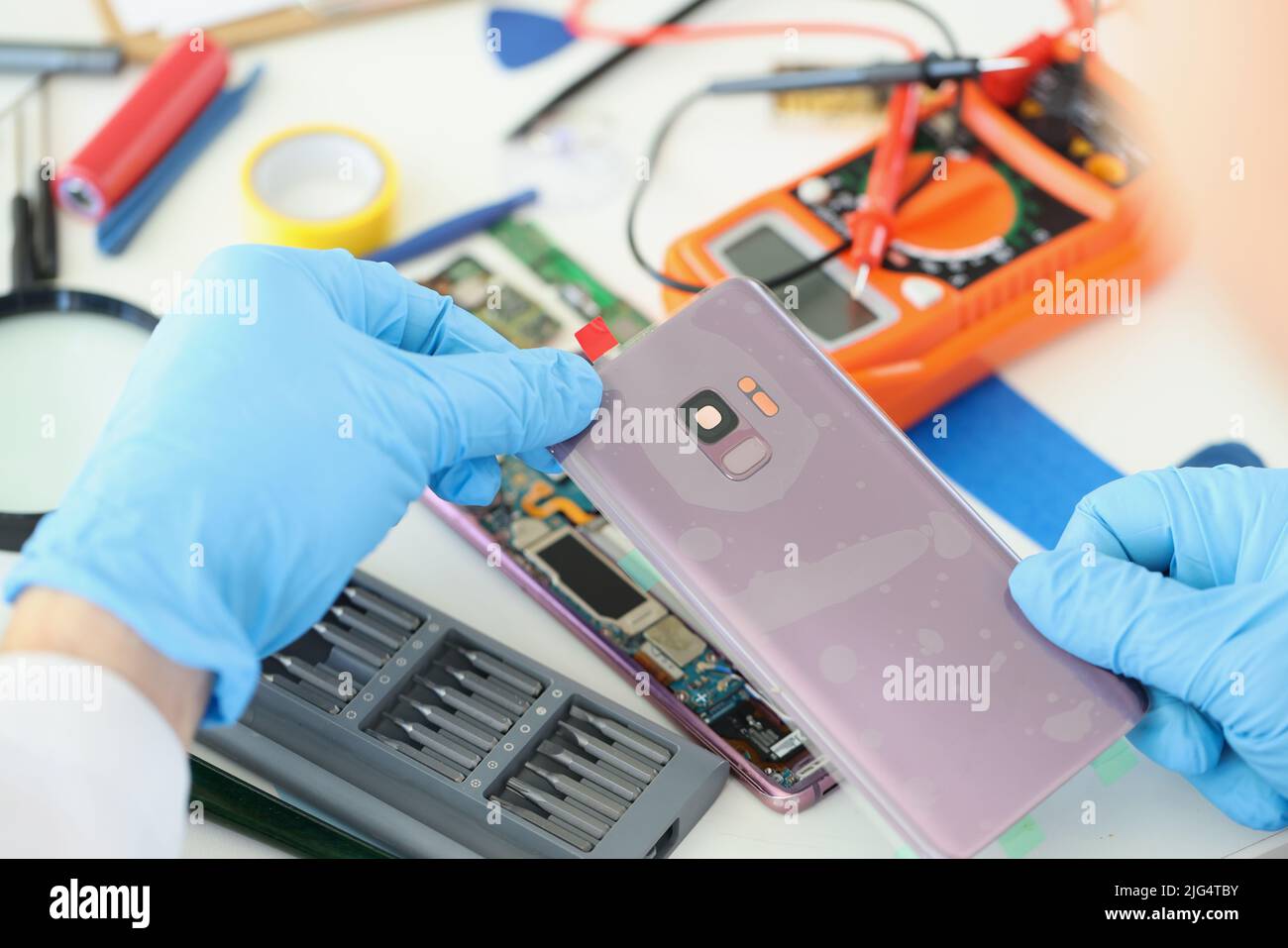 Technician repairs broken smartphone at table in workshop Stock Photo