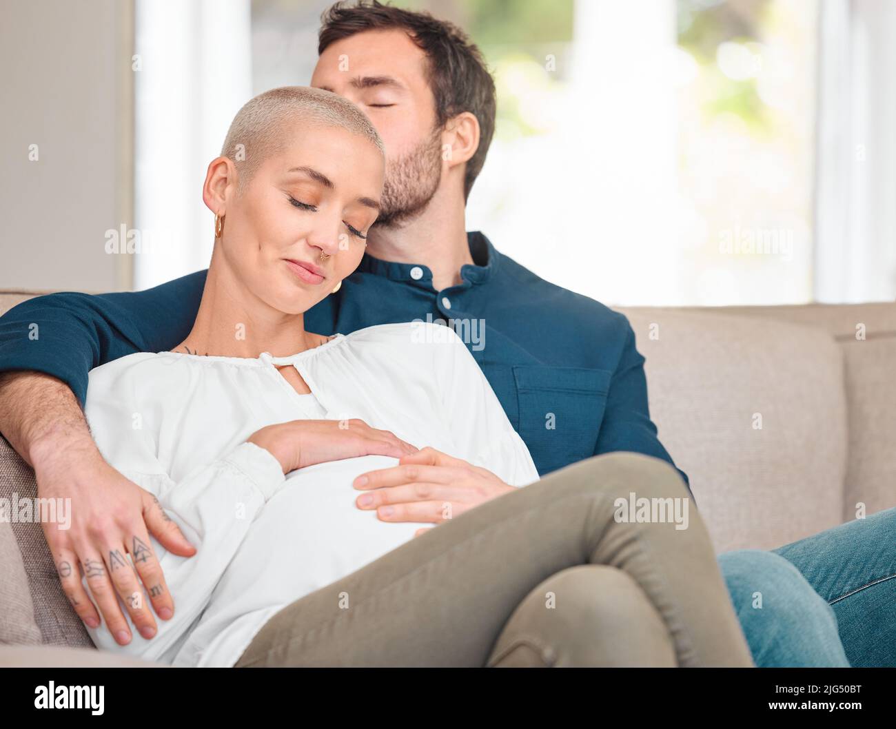 Starting a family. Cropped shot of an affectionate young expectant couple sitting on the sofa at home. Stock Photo