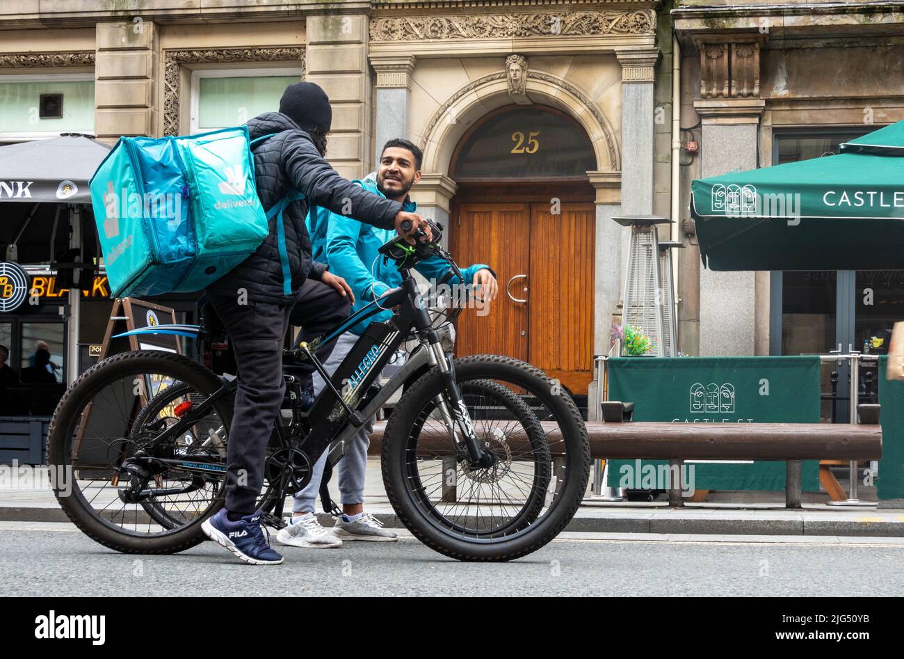 Two Deviveroo bicycle delivery men stopping for a friendly chat on Castle Street in Liverpool Stock Photo