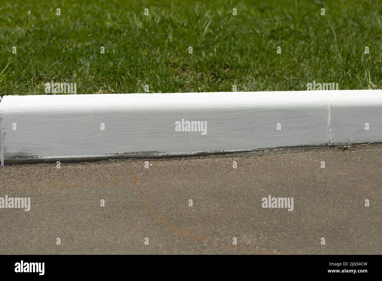 Painted curb. White curb on road. Landscaping in city. White paint