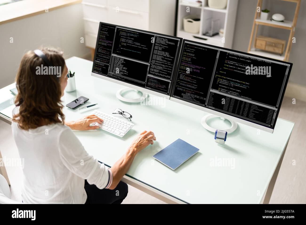 Female Programmer Working On Multiple Computer Screens Stock Photo - Alamy