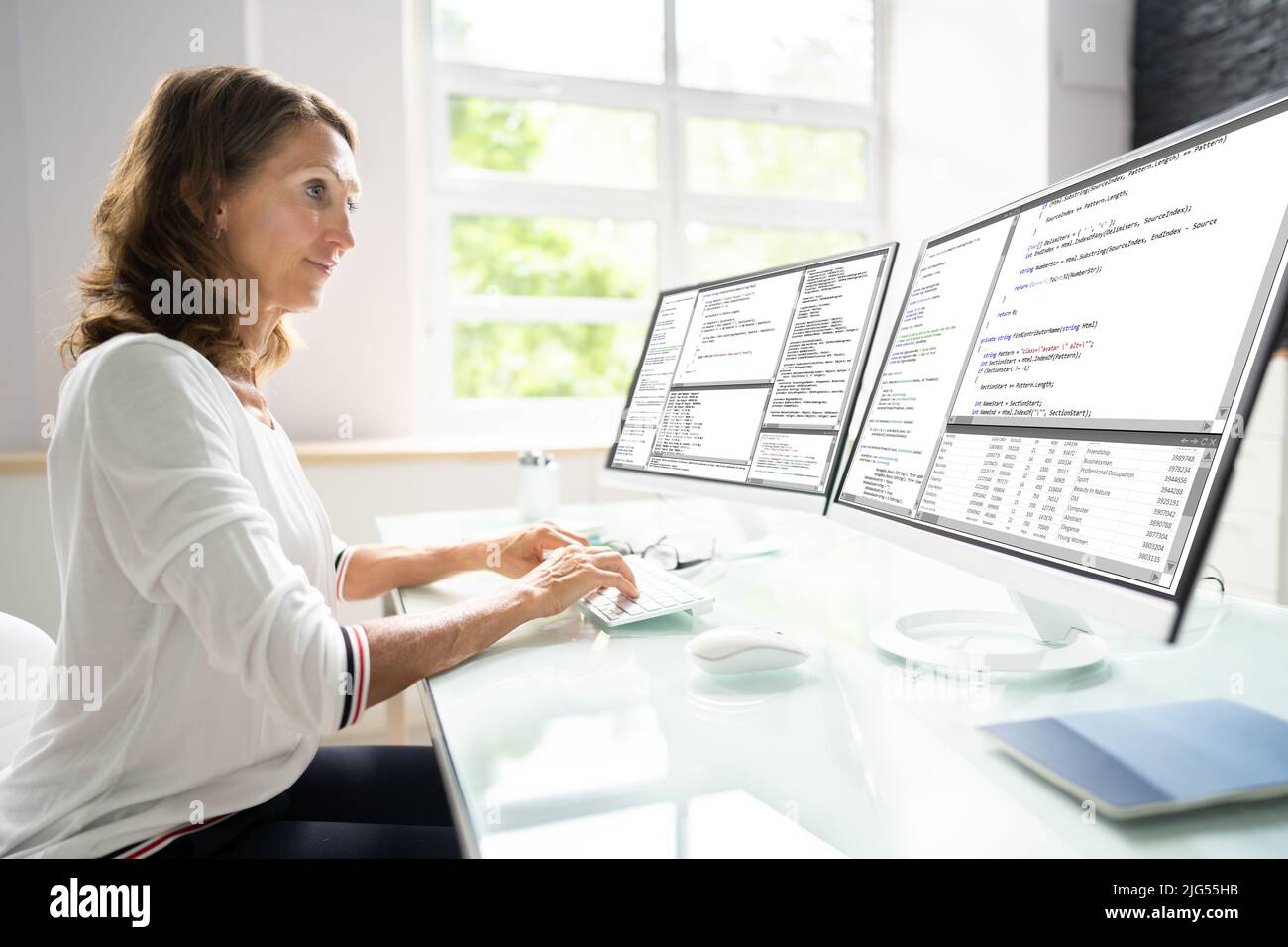 Programmer Woman Coding On Multiple Computer Screens Stock Photo - Alamy