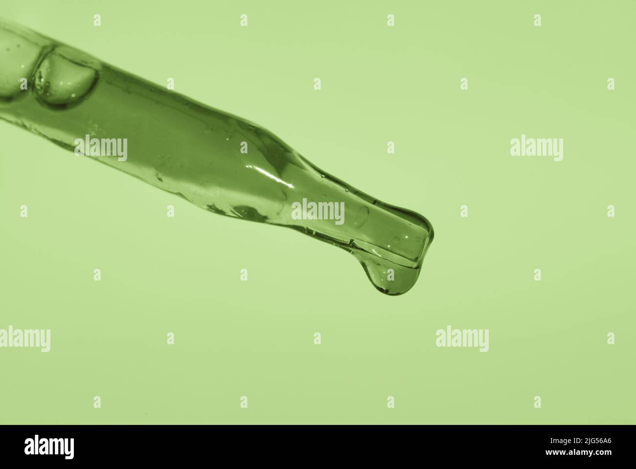 Pipette with green extract on a green background. Thick consistency, aloe pulp. The concept of a plant extract for cosmetic and medicinal purposes. High quality photo Stock Photo