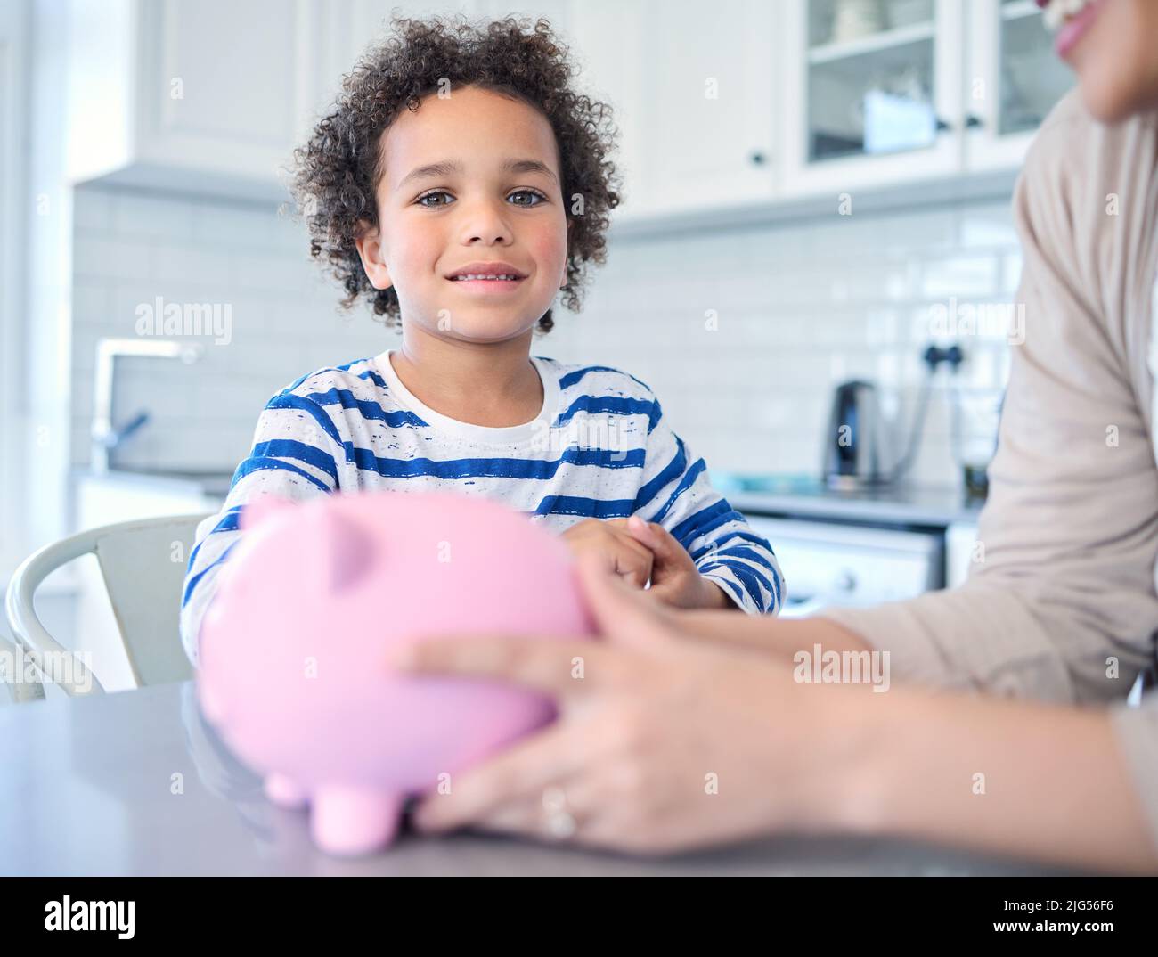 Saving got a rainy day. Shot of a young mother teaching her son about savings at the kitchen table. Stock Photo