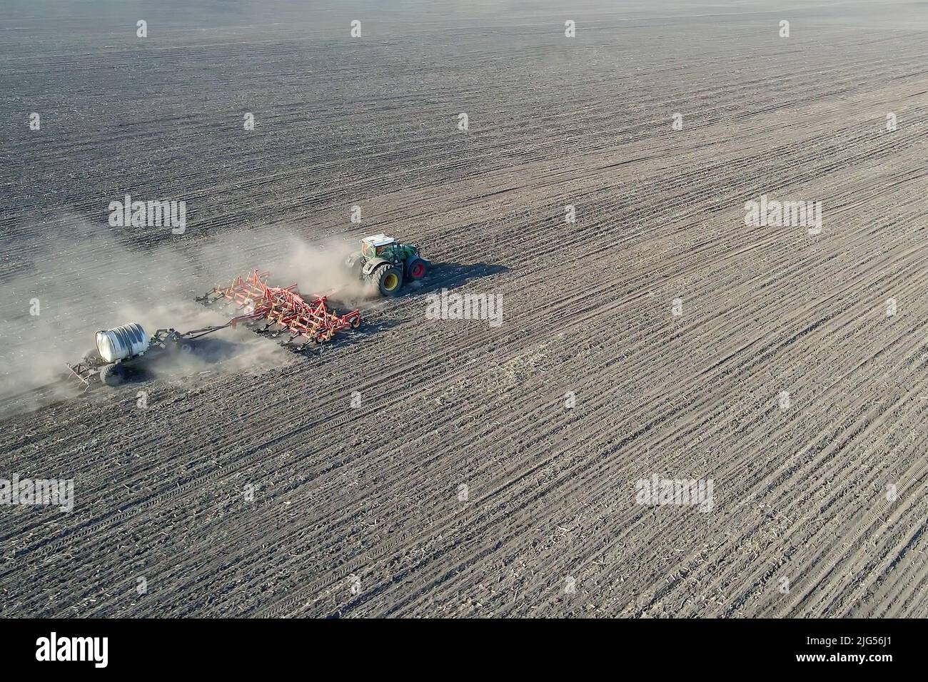 Tractor with trailed agricultural machinery plowing and apply fertilizers  Stock Photo