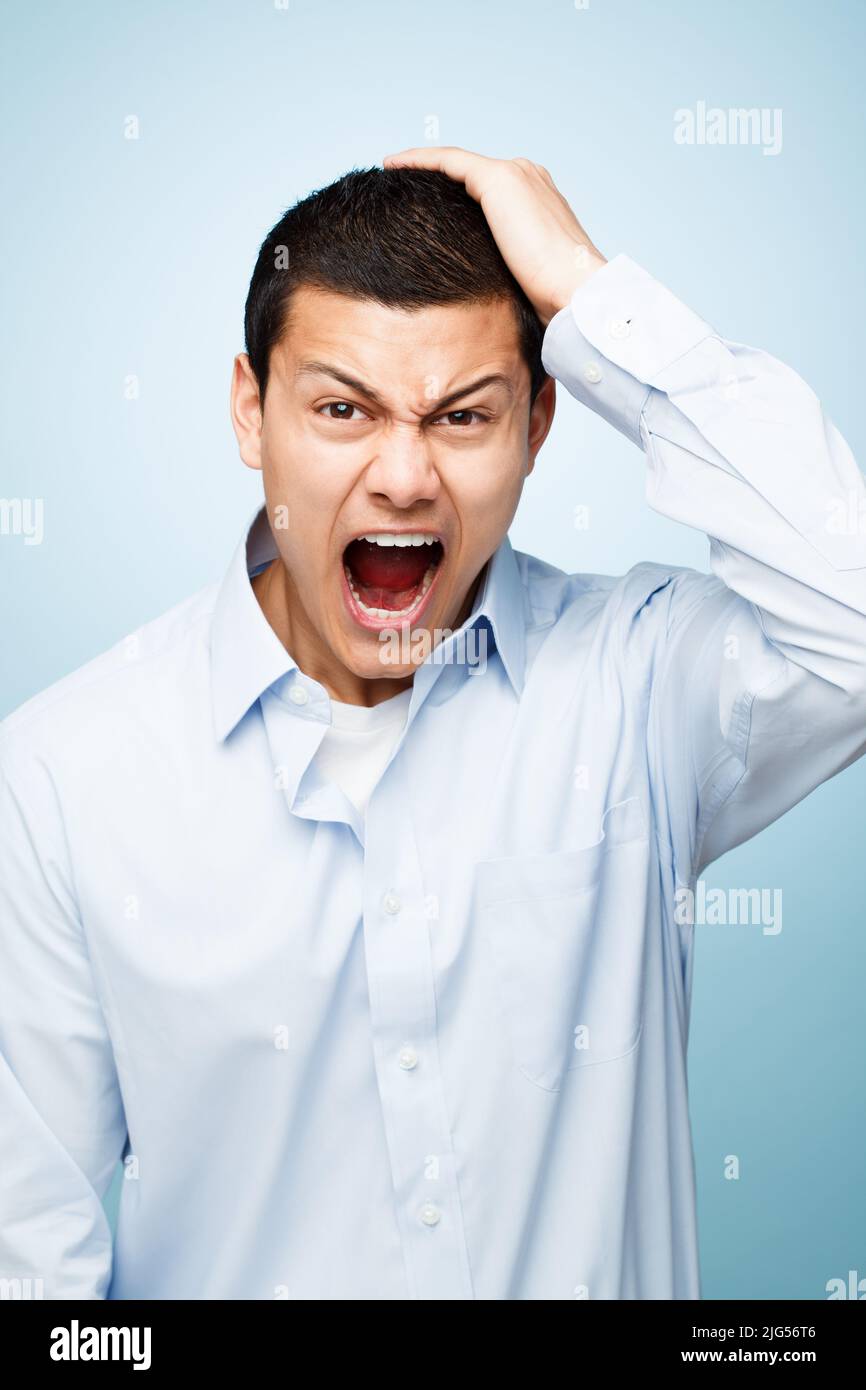 These are the days I hate. Shot of a young man pulling his hair in frustration against a studio background. Stock Photo