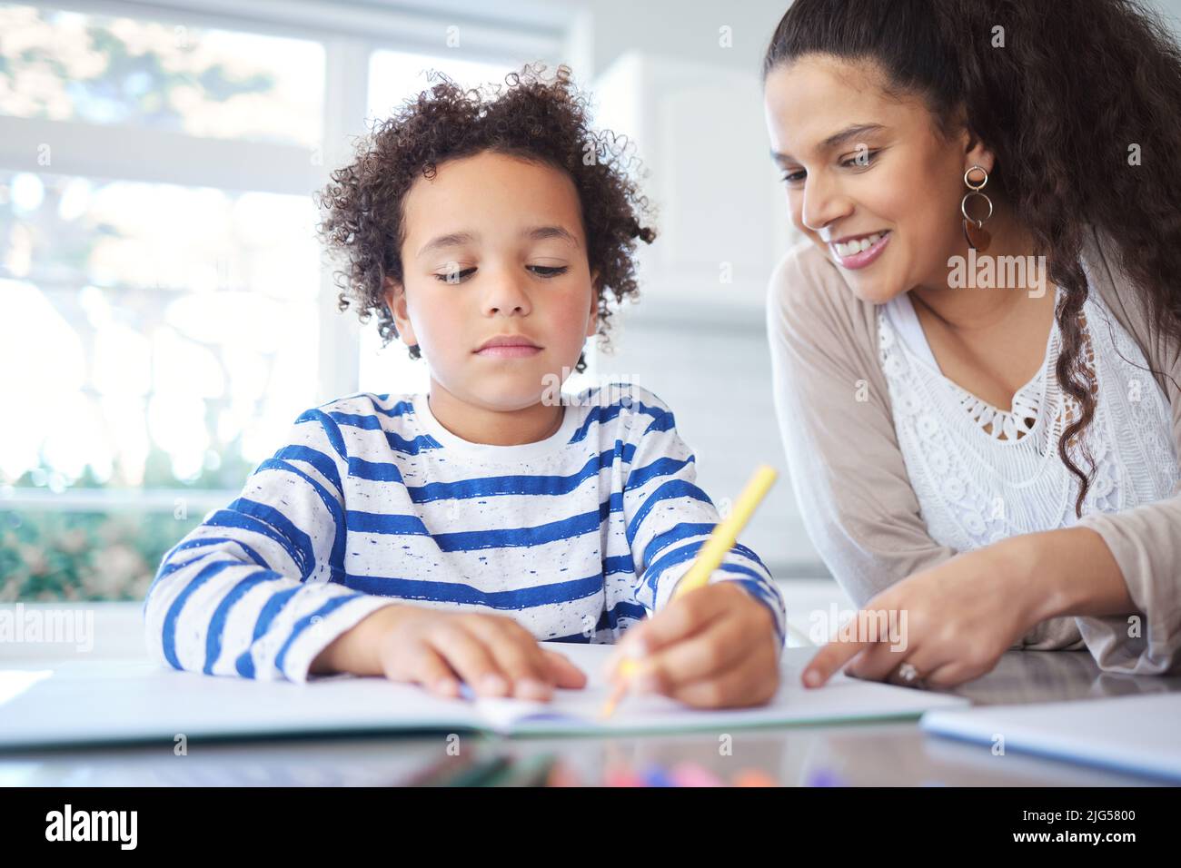 Hes really talented. Shot of a mother helping her son with homework at ...