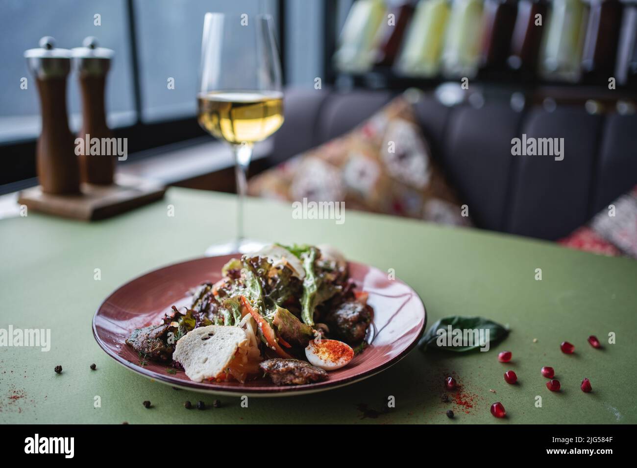 salad with chicken liver, egg and crouton or wine in glass on restaurant table Stock Photo