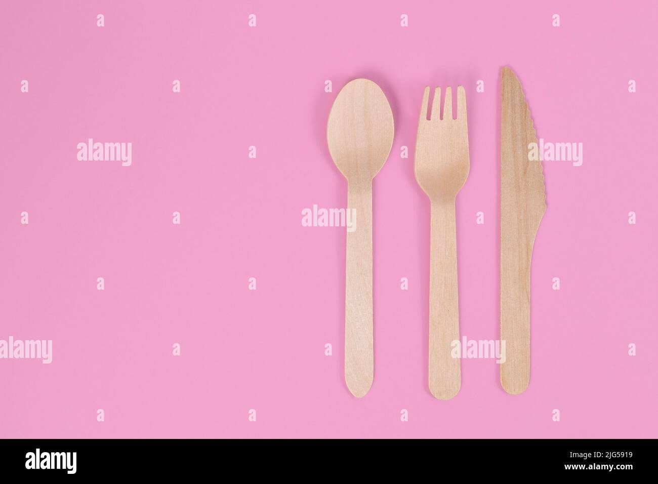Wooden cutlery on side of pink background with copy space Stock Photo