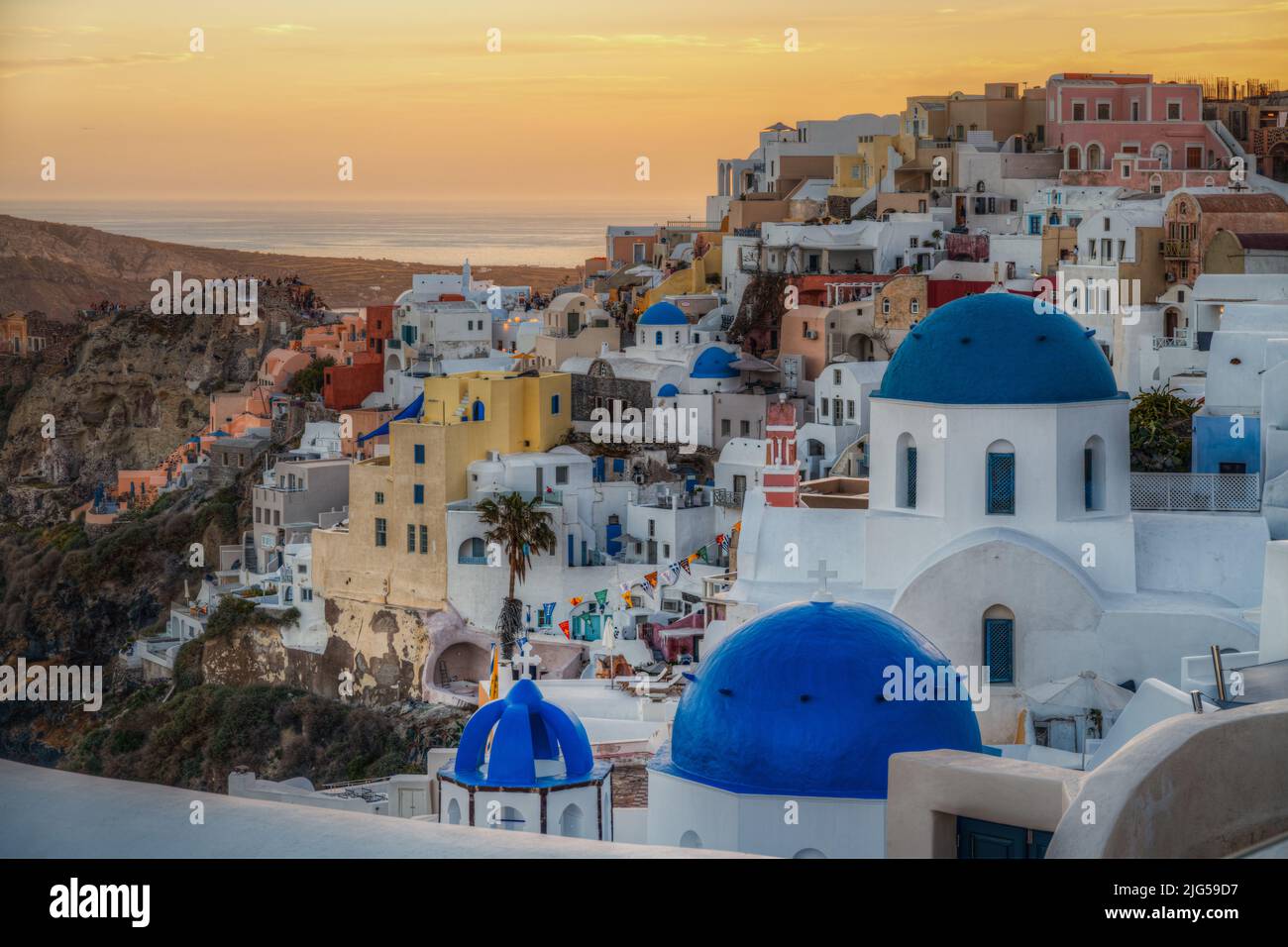 Scenic panoramic view of Oia village at sunset with the iconic blue domed church in the foreground, Santorini, Greece Stock Photo