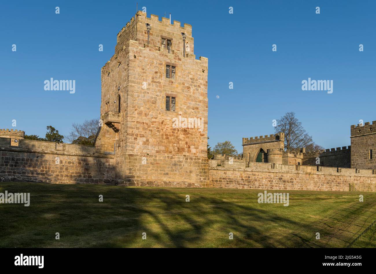 King James IV tower at Ford Castle, Northumberland in warm evening sunlight with a clear blue sky and near full moon. Stock Photo
