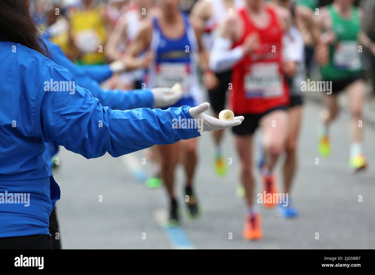 employees give the marathon runners pieces of banana as food Stock Photo