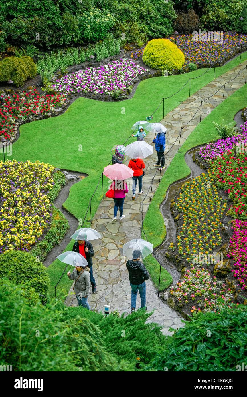 People with umbrellas, Sunken Garden, Butchart Gardens, Brentwood Bay, Greater Victoria, British Columbia, Canada Stock Photo
