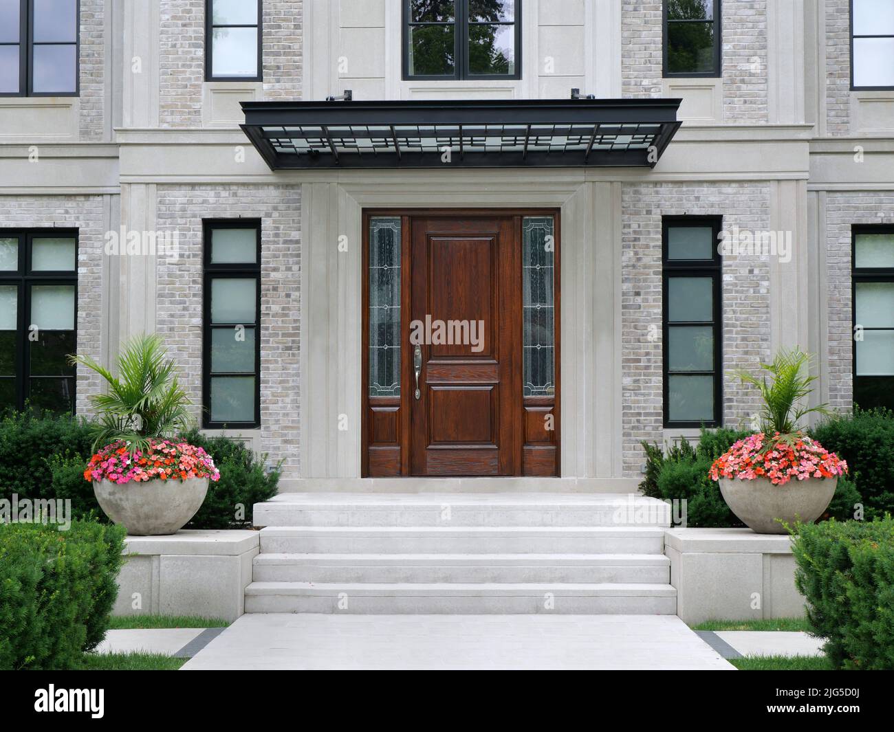 House entrance with elegant wood grain front door with sidelights Stock Photo