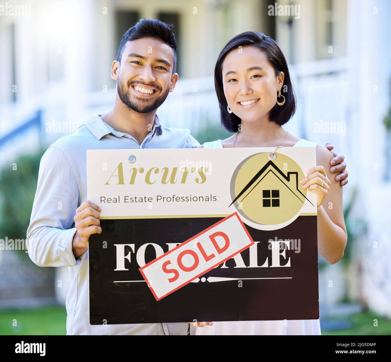 Its the start of a new journey. Shot of a young couple holding up a sold board outside their house. Stock Photo