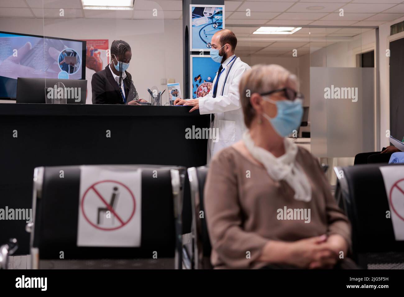 General practitioner chatting with hospital receptionist during ...