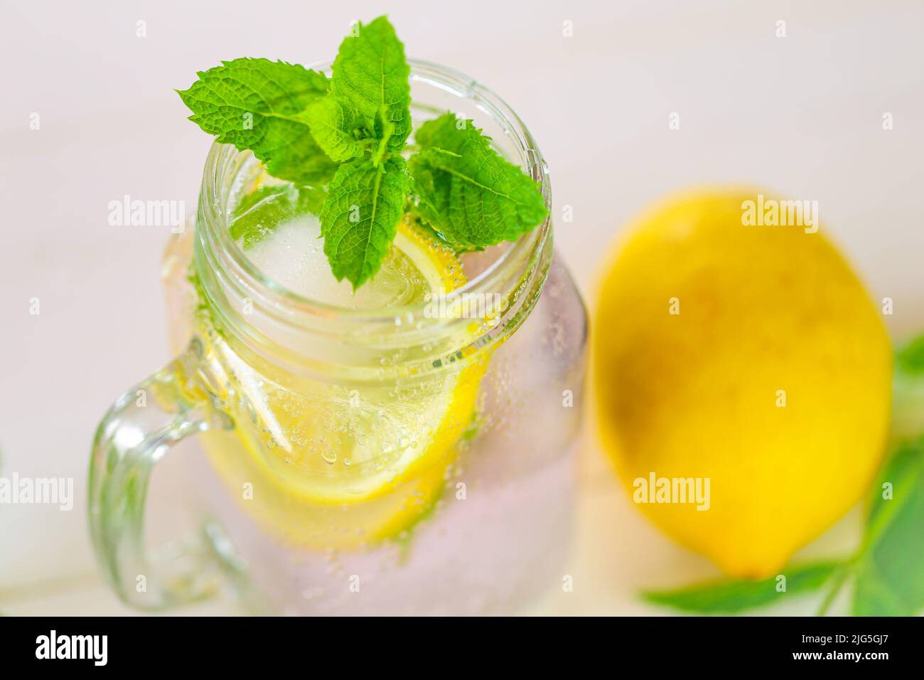 Lemon mint water with ice in a transparent mug. cocktail with mint leaves. Sassy lemon water.Lemon summer drink.Dietary lemon drink. Stock Photo