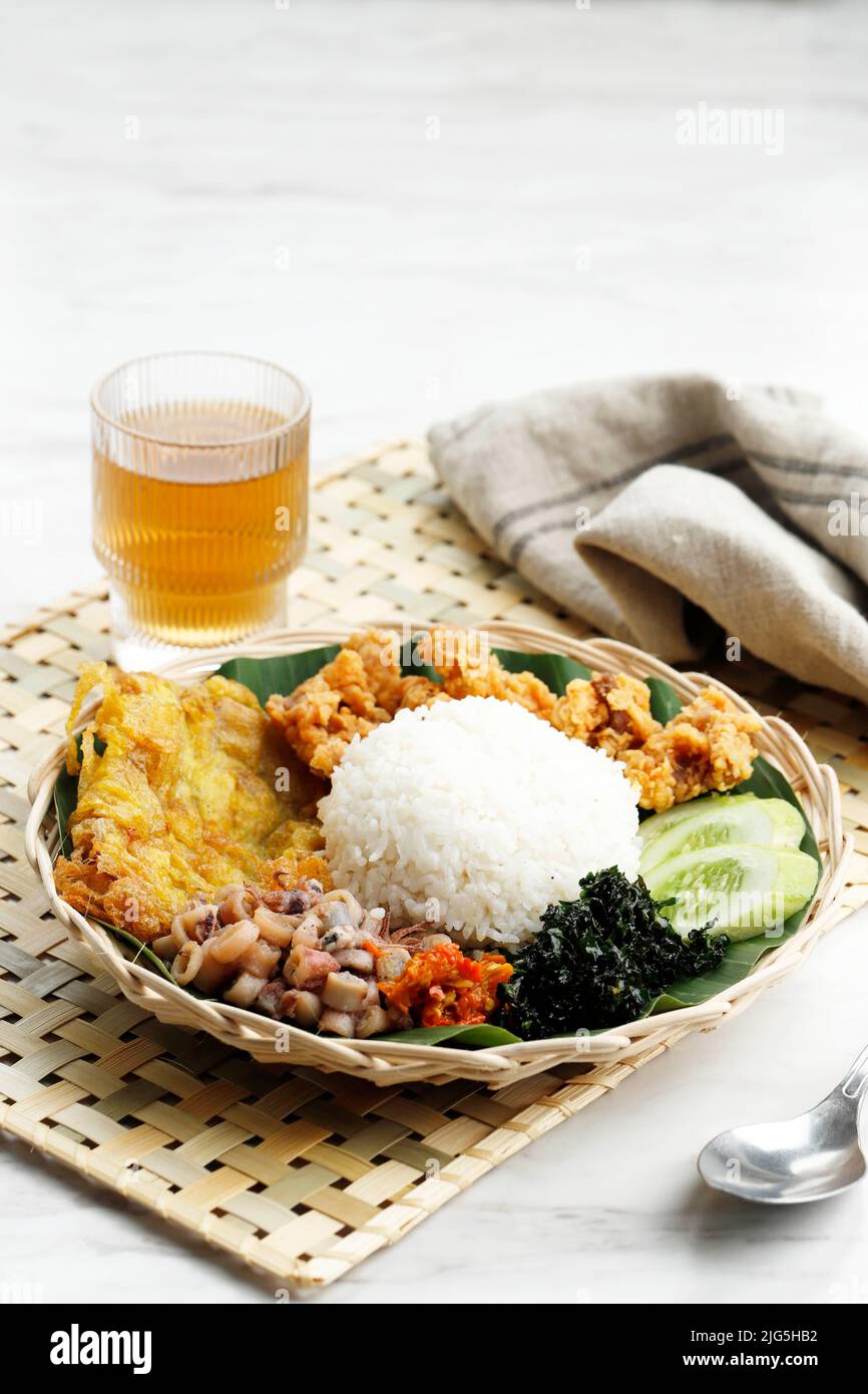 Close Up Nasi Campur Cumi Asin Surabaya, White Rice with Sautee Salted Squid, Sambal, Egg, and Boiled Cassava Leaf. Stock Photo