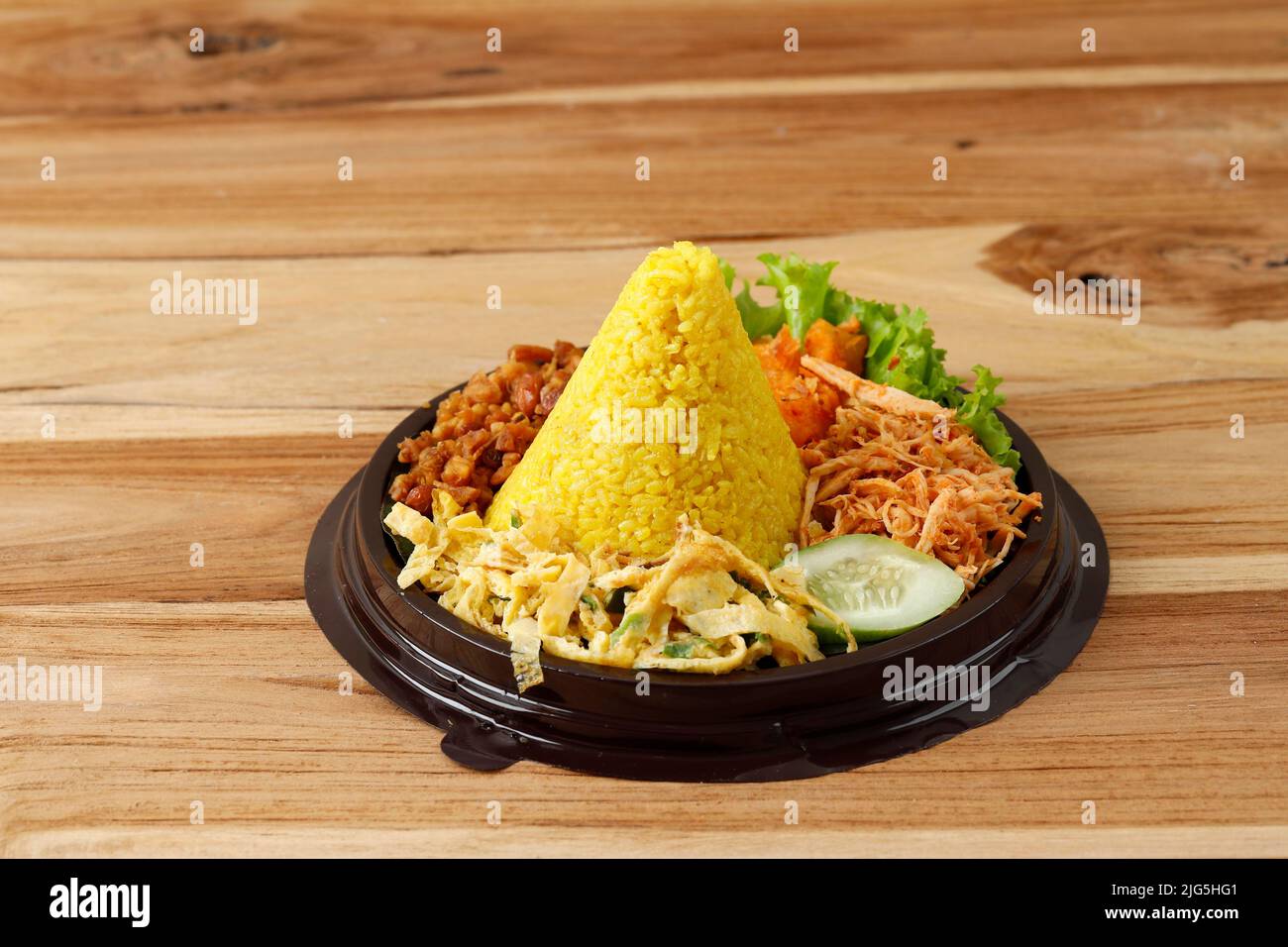 Mini Tumpeng Made of Yellow Rice with Some Side Dishes, Ready to Eat, Served for Agustusan Indonesia Independence Day. On Wooden Table Stock Photo