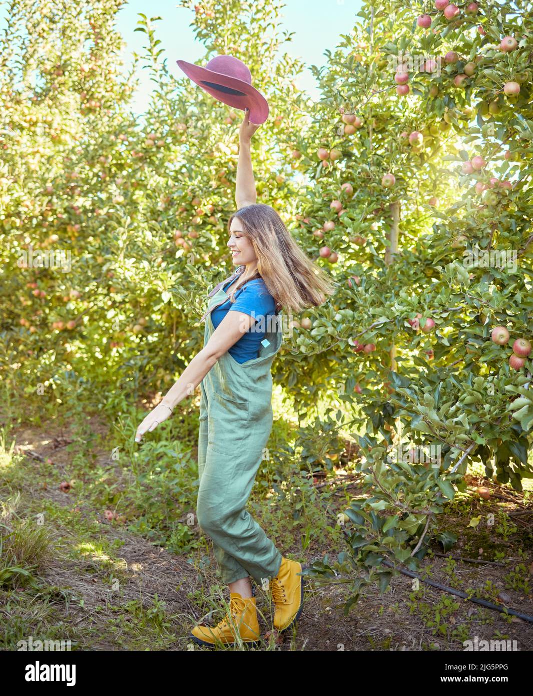 Cheerful farmer feeling optimistic and fulfilled for harvest season of fresh organic fruit. One excited energetic happy young woman jumping for joy on Stock Photo