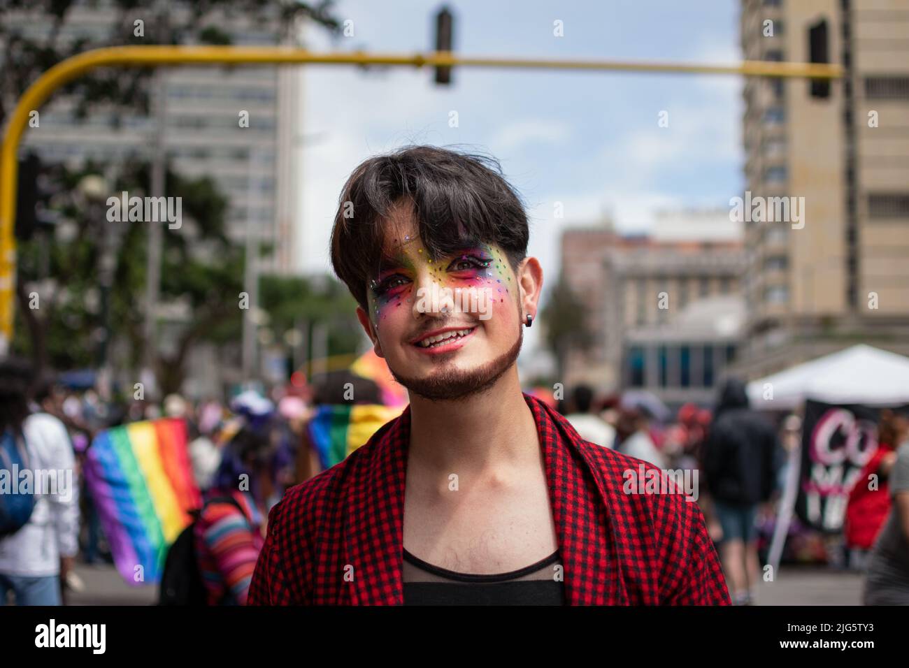 Man with lgtbiq+ flag painted on his face smiles as he attends pride celebration in Bogota. Stock Photo