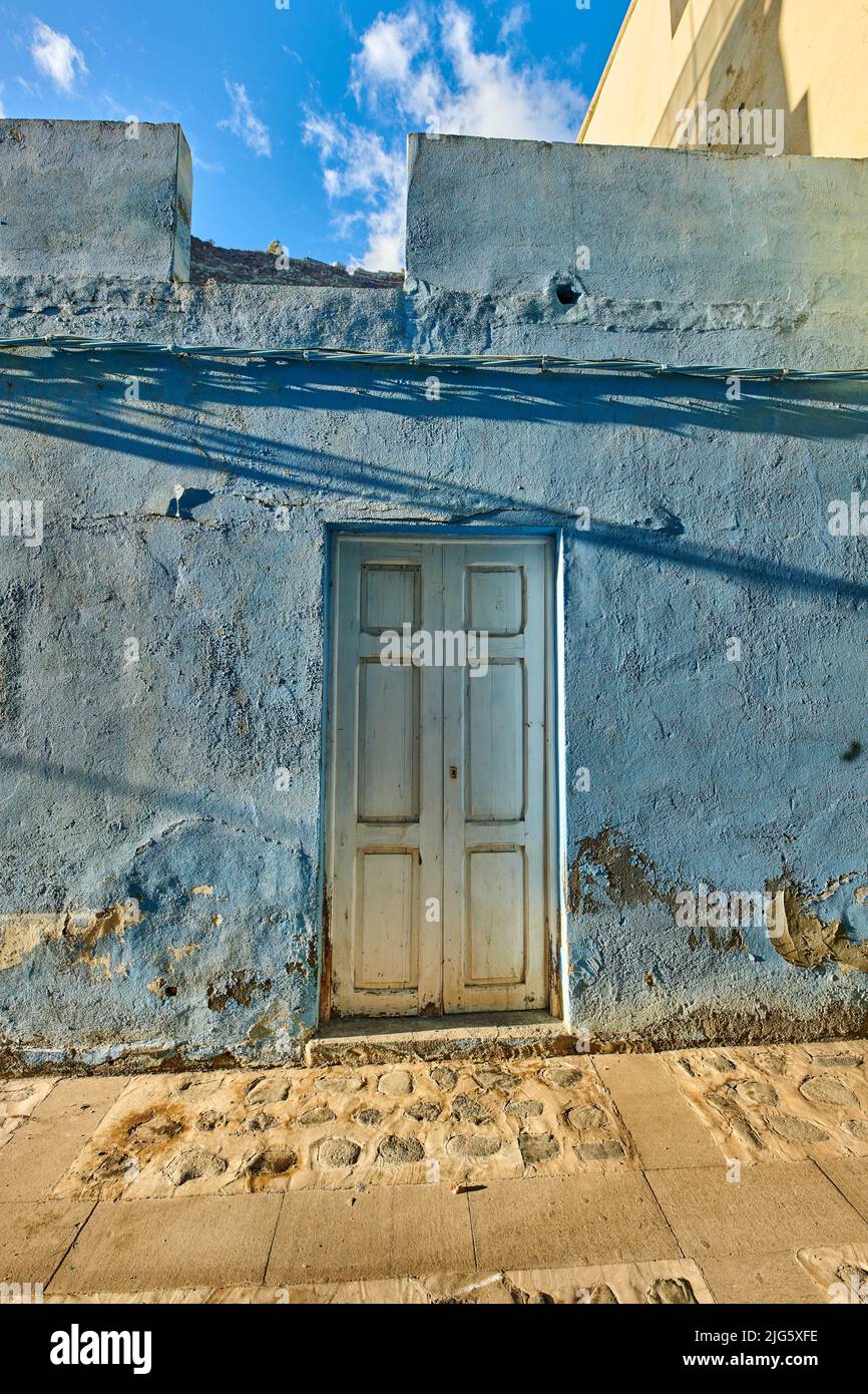 Old abandoned house or home with a weathered blue wall and wooden door ...