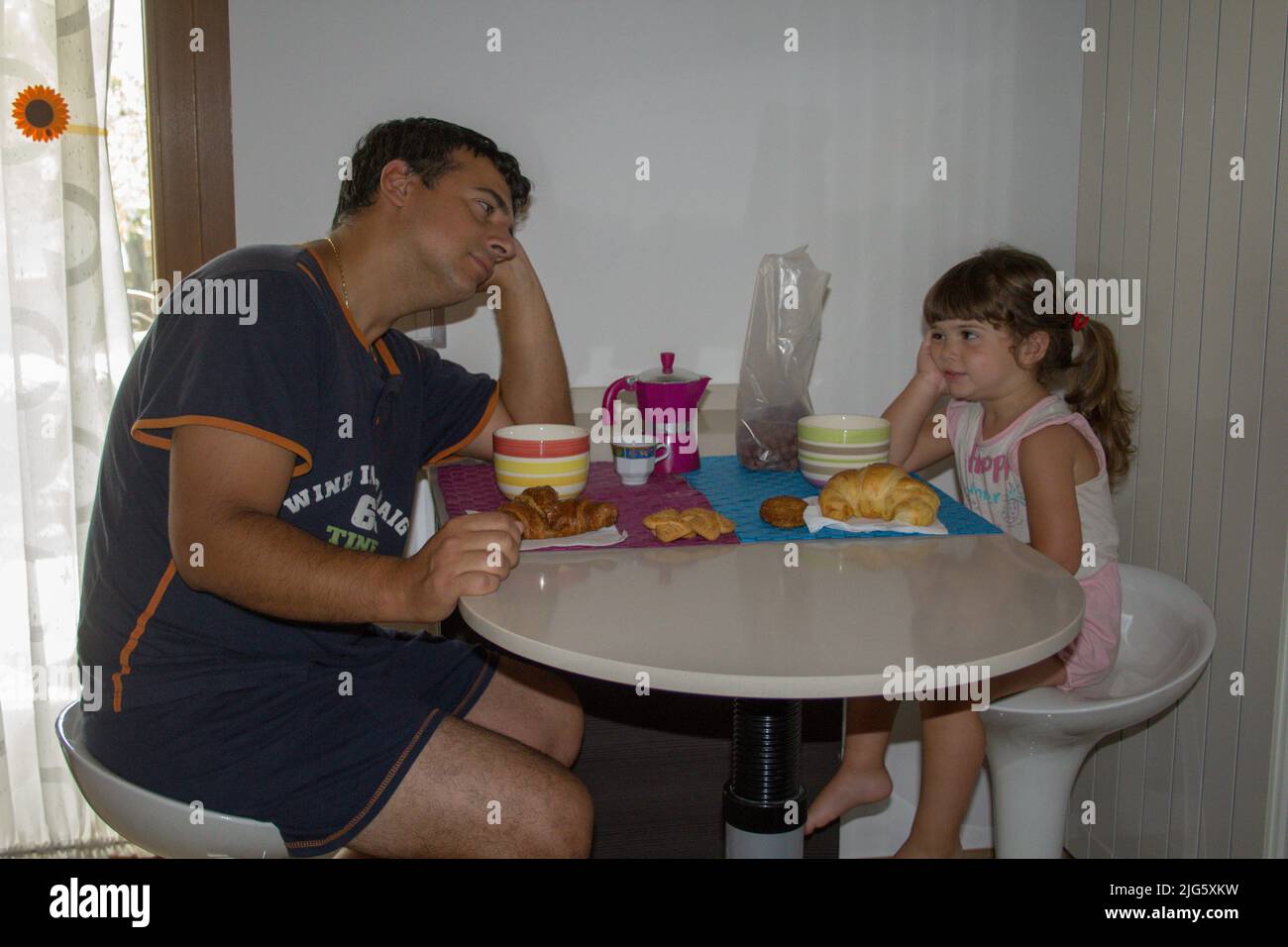 Picture of a sleepy and just waking up dad with his daughter while having breakfast in the morning. Stock Photo