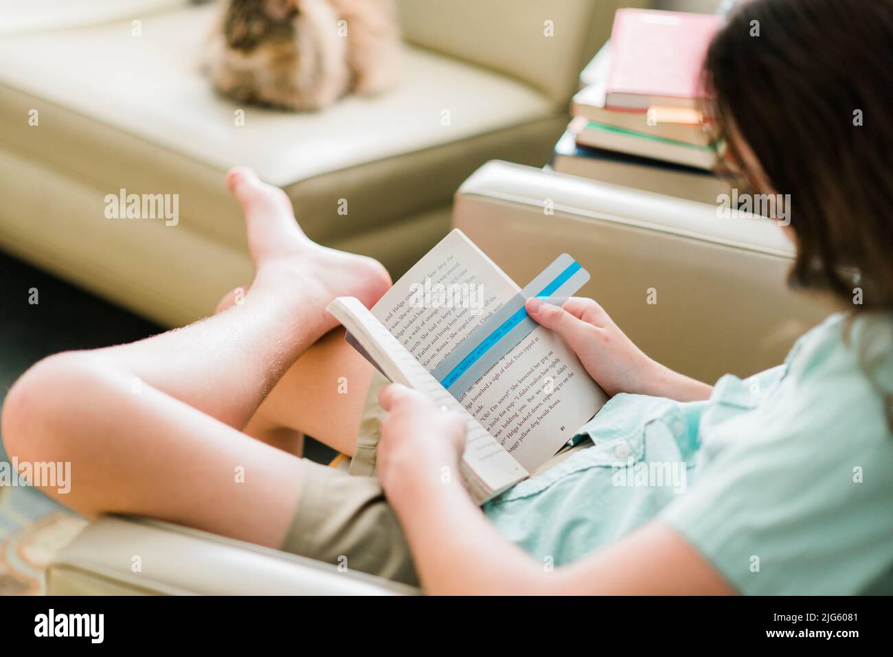 Dyslexic child reading with dyslexia color overlay in his book. A blue color overlay on the page makes it easier to read. Stock Photo