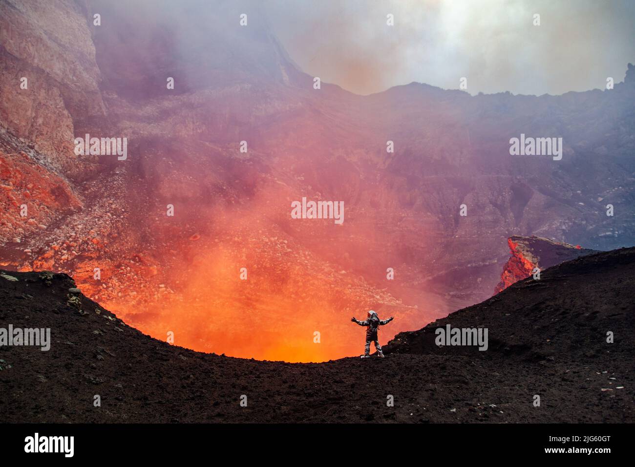 An explorer wearing a heat proximity suit celebrates getting inside the crater and close to the lava lake inside the Marum vent on Ambrym island in Va Stock Photo