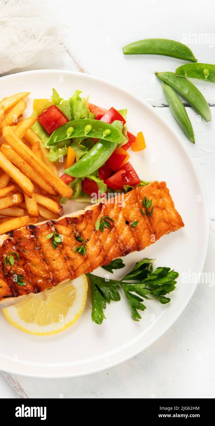 Salmon steak with vegetables and fries on light background. Freshly ...