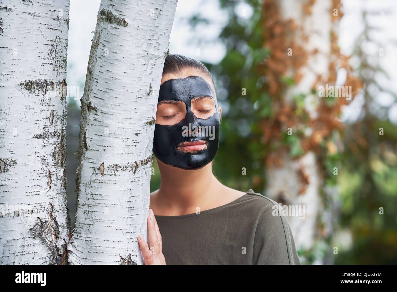 Young woman in nature with black mask on face Stock Photo