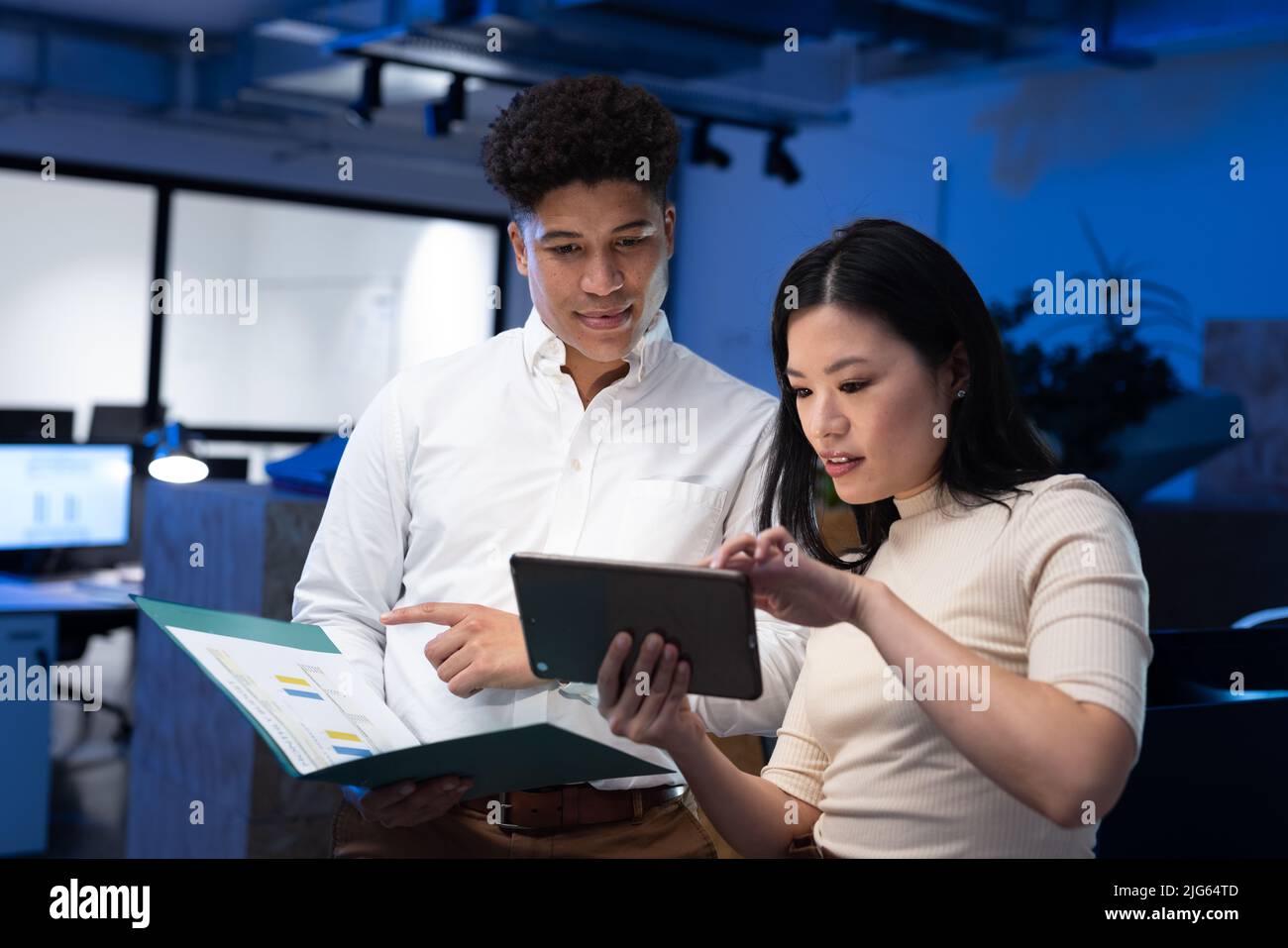 Asian male and female professionals analyzing report over digital tablet in office at late night Stock Photo