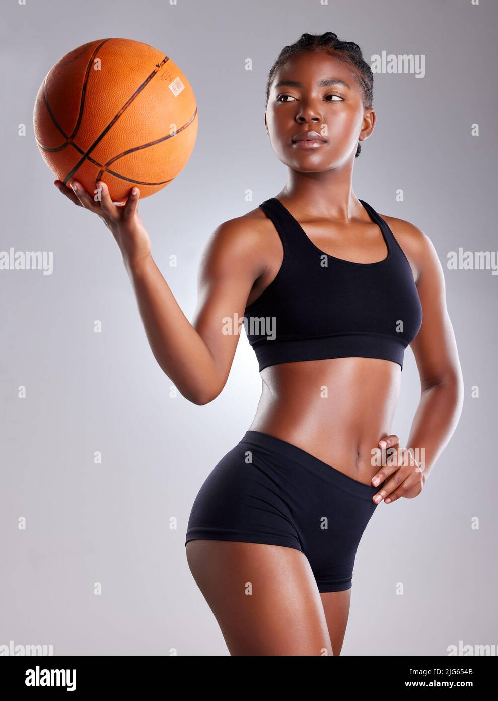How many hoops can you shoot. Studio shot of a sporty young woman posing with a basketball against a grey background. Stock Photo
