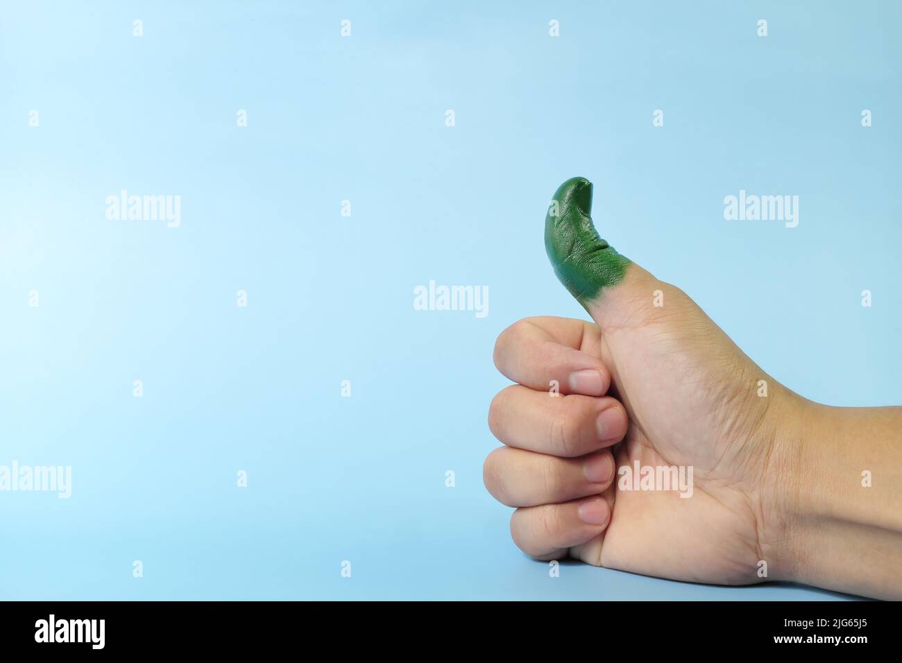 Green thumb and environmentalist concept. Human thumb up painted with color green. Stock Photo