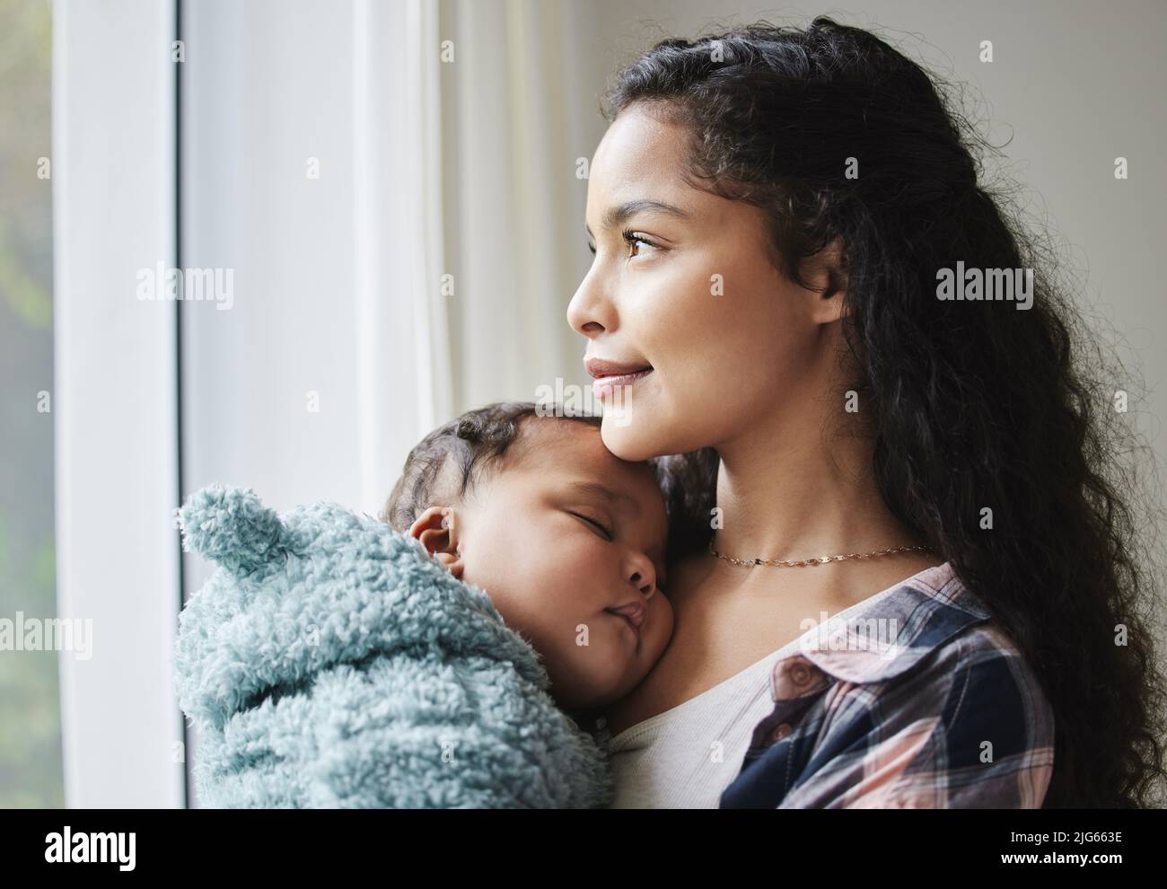 Motherly love is everything. Shot of a young mother looking out of a window  while holding her baby at home Stock Photo - Alamy