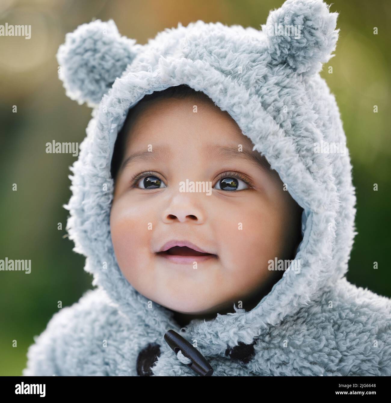 So beary cute. Shot of an adorable baby boy wearing a furry jacket with bear ears outdoors. Stock Photo