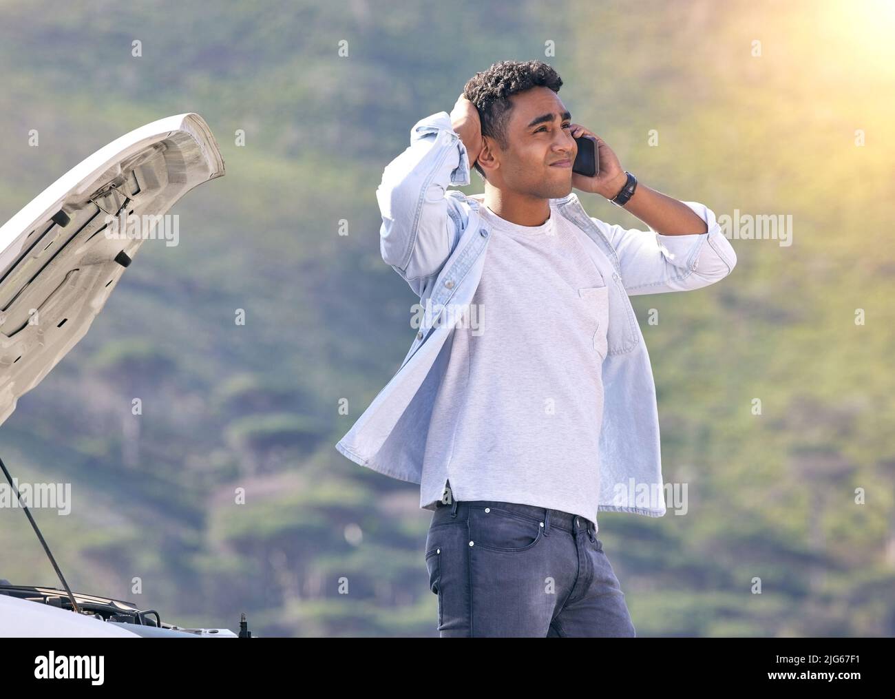 When can you guys get here. Cropped shot of a handsome young man on the phone with roadside assistance after suffering a vehicle breakdown. Stock Photo