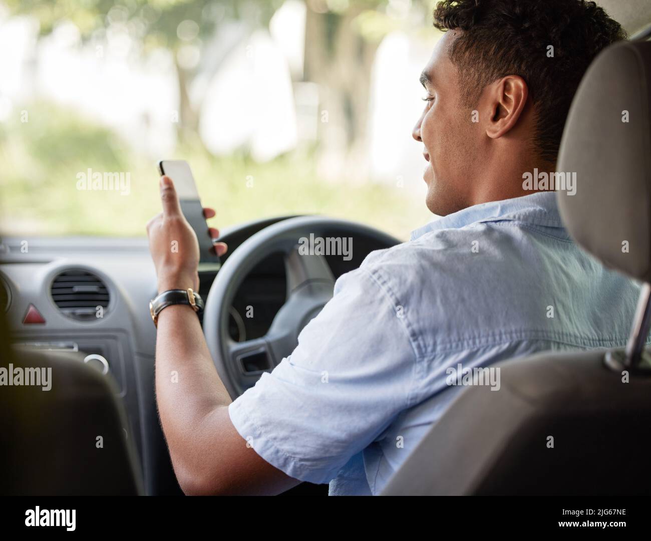He never gets lost while going about logistics. Shot of a young delivery man using a cellphone while sitting in a van. Stock Photo