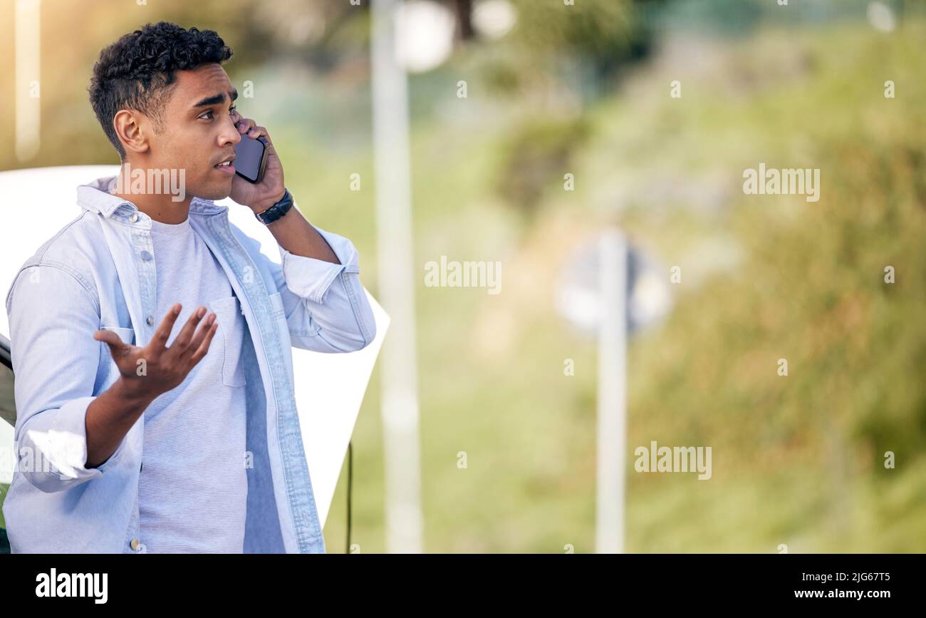 So, how long. Cropped shot of a handsome young man on the phone with roadside assistance after suffering a vehicle breakdown. Stock Photo